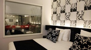 A bedroom with a large window, a bed with black and white bedding, and a wall with a black and white pattern. - Vert Jerusalem (Jerusalem)