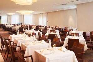 Un salón de banquetes con mesas dispuestas para comer, organizadas en filas.