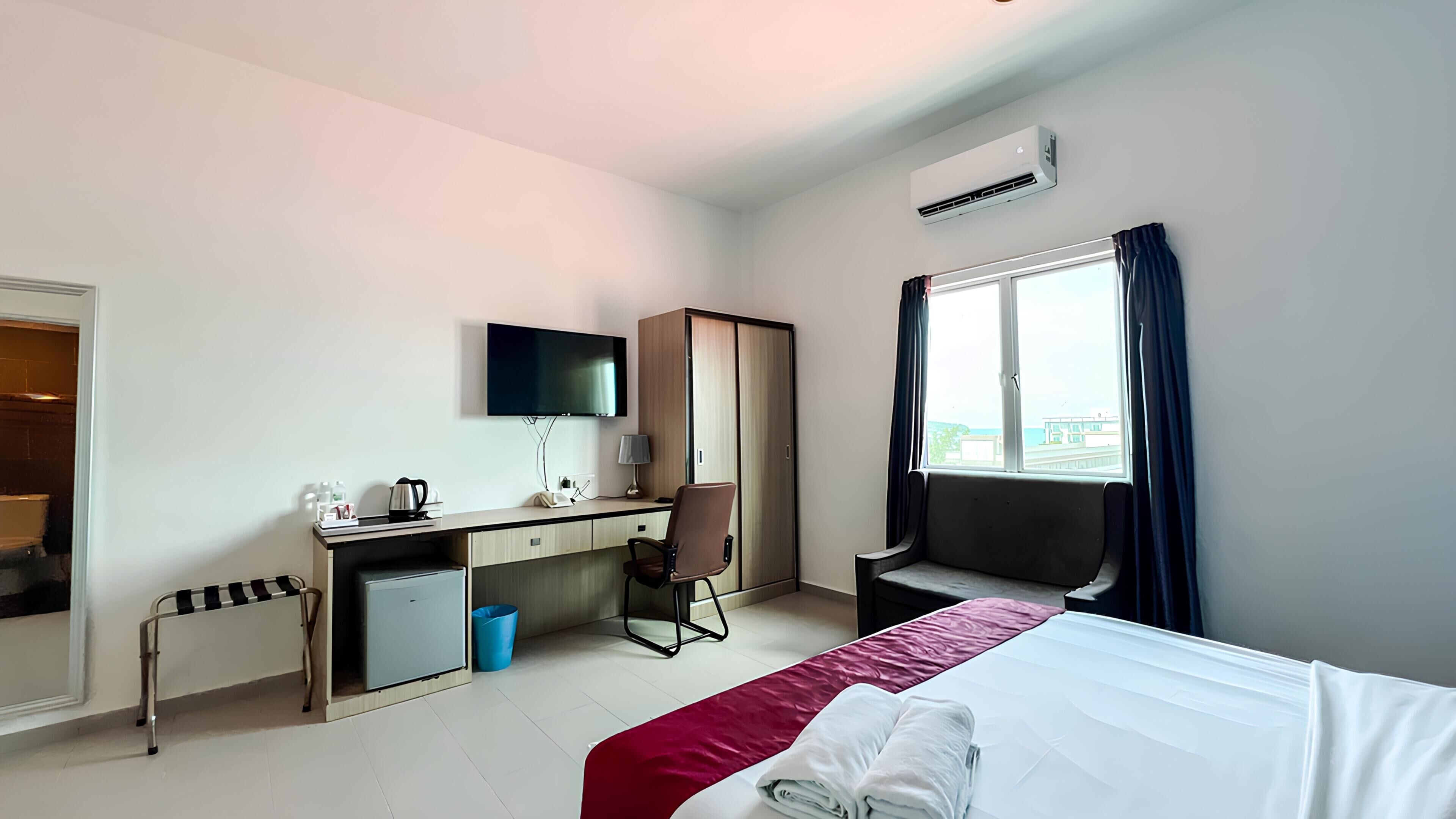 A hotel room with a bed, desk, chair, TV, and window.