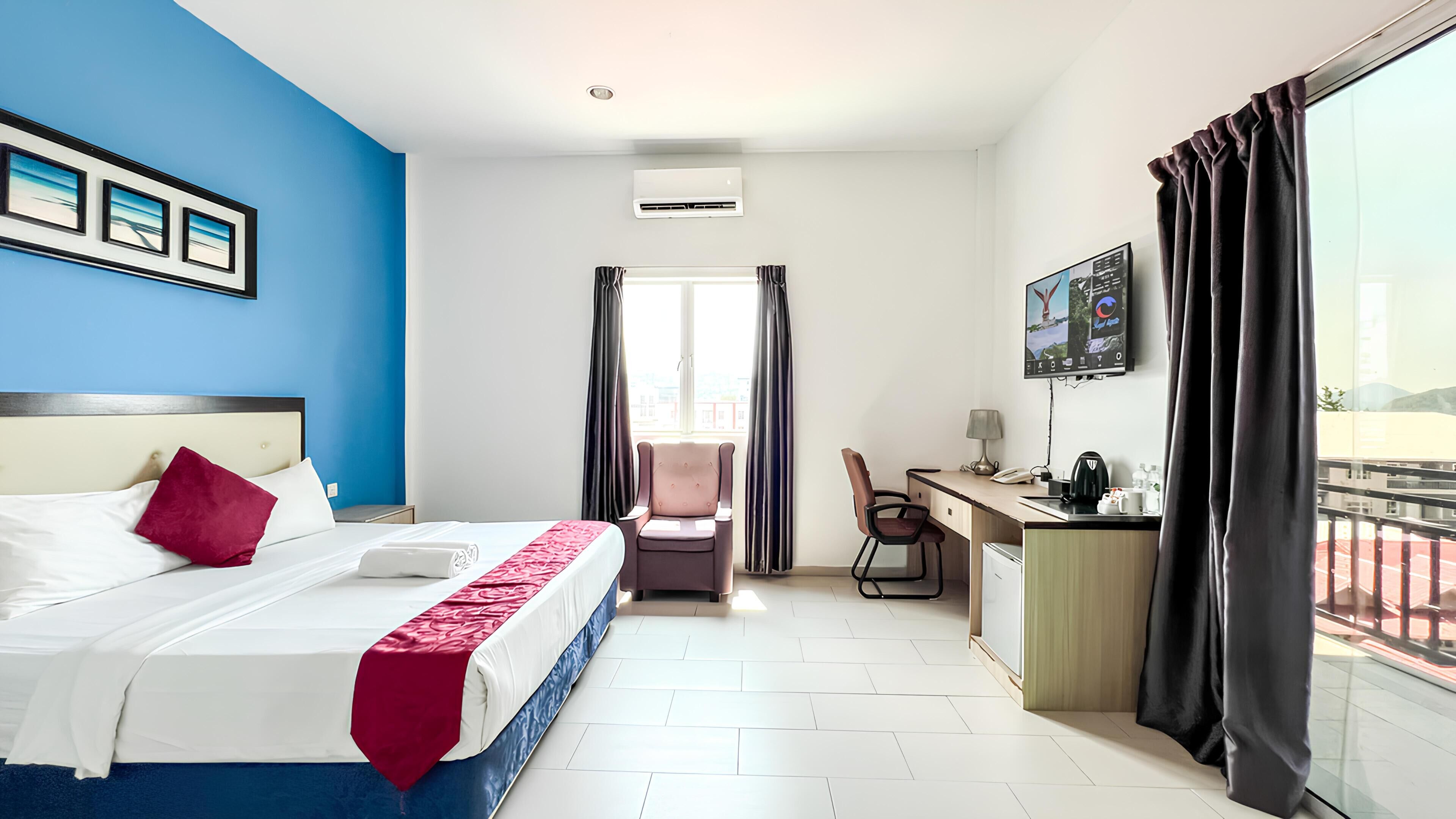 Een hotelkamer met een bed, bureau, stoel en een raam met gordijnen.