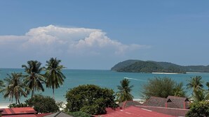 A coastal view with palm trees, a beach, and a mountain in the distance. - Royal Agate Beach Resort (Langkawi)