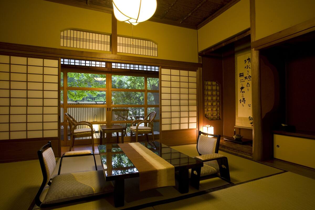 A traditional Japanese room with tatami flooring, low tables, and sliding doors.