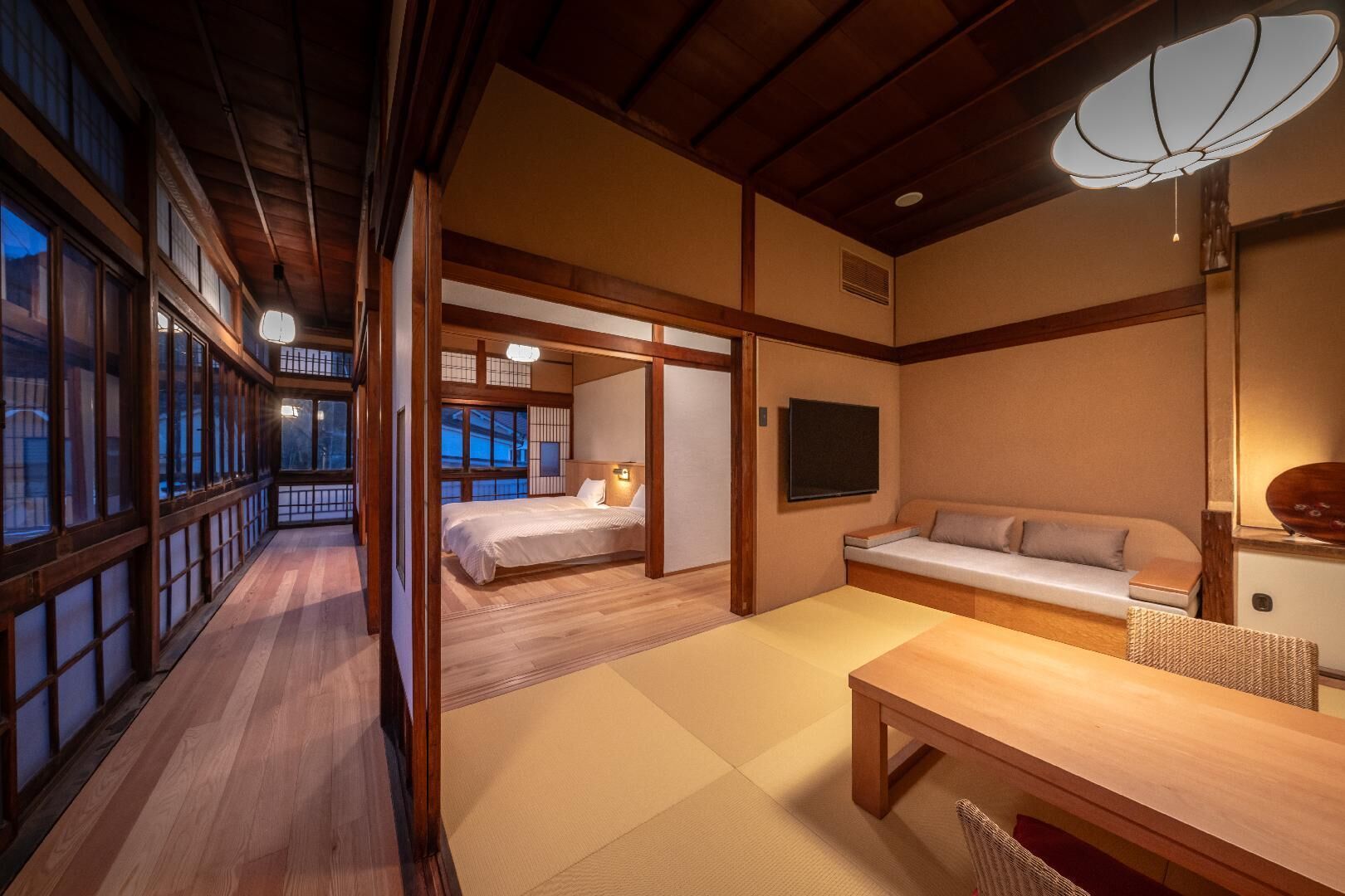 A traditional Japanese room with tatami flooring, a bed, a sofa, and a table.