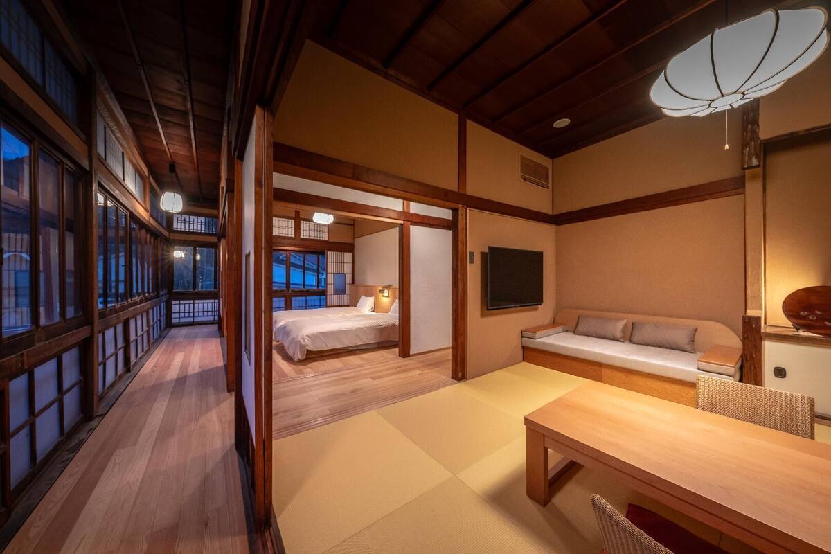A traditional Japanese room with tatami flooring, a bed, a sofa, and a table.