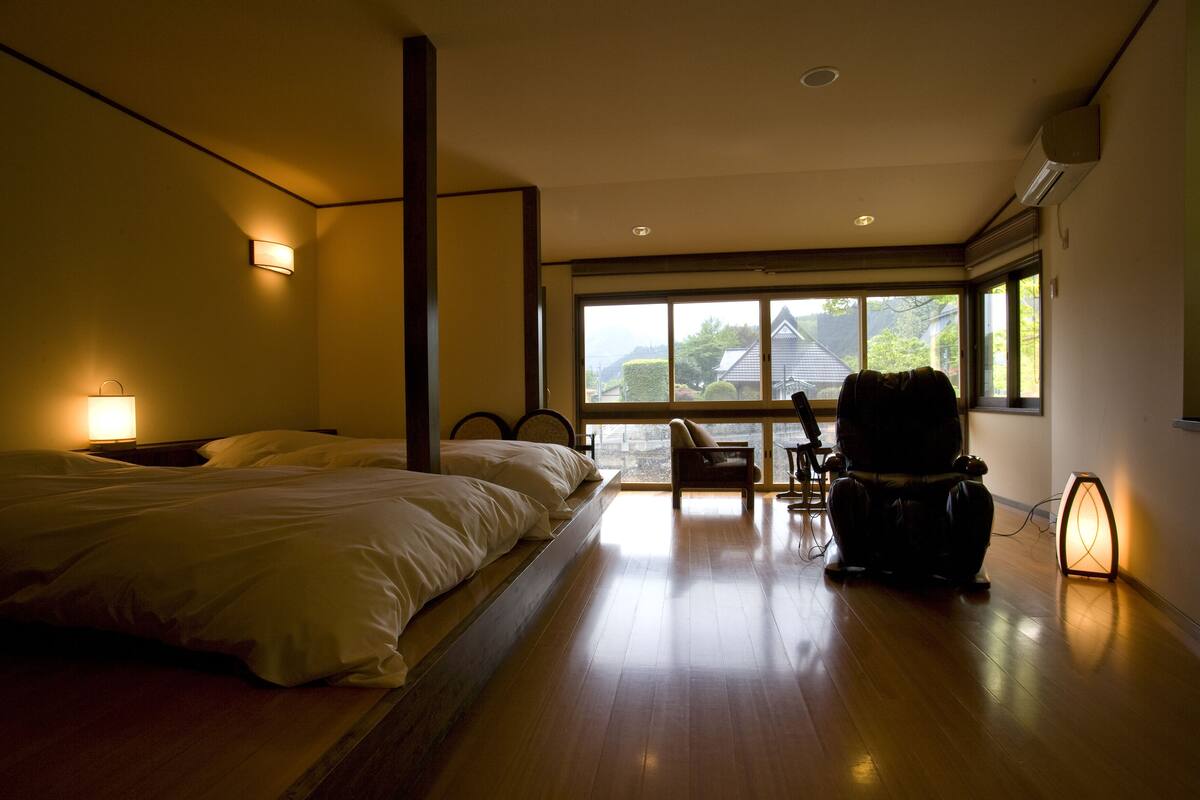 A bedroom with a large bed, a chair, and a view of the outdoors.