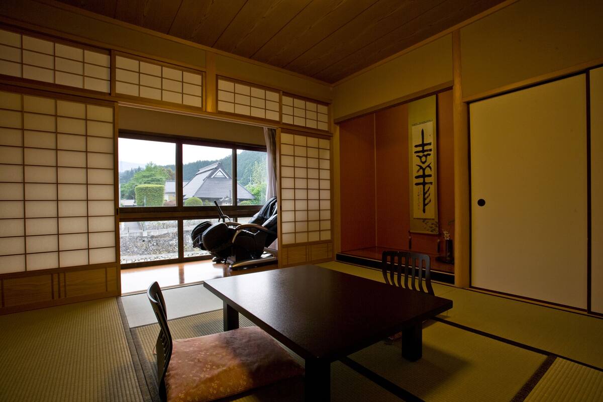 A traditional Japanese room with tatami flooring, a low table, and a sliding door.