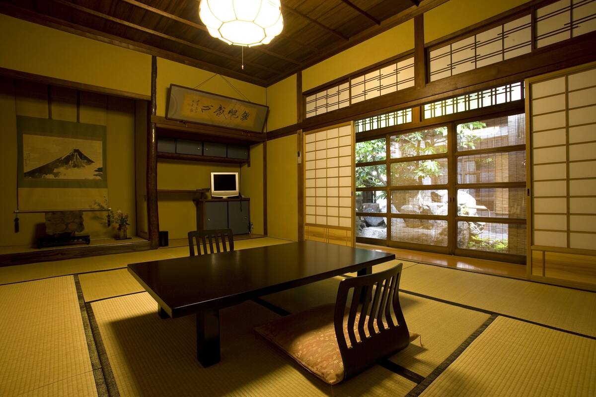 A traditional Japanese room with tatami flooring, a low table, and sliding doors.