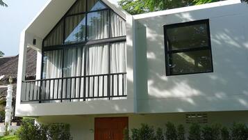 A modern two-story building with large windows, a balcony, and a wooden door.