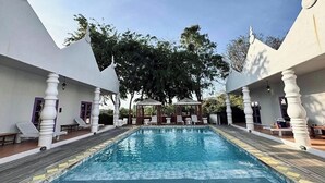 Zona de piscina con vistas despejadas a la piscina, sillas de descanso y un pabellón al fondo.