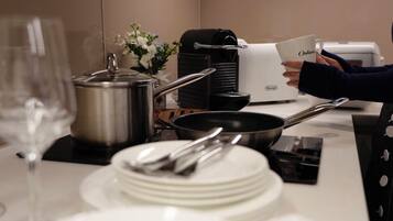 A kitchen with a coffee maker, a pot, a pan, and a stack of white plates.