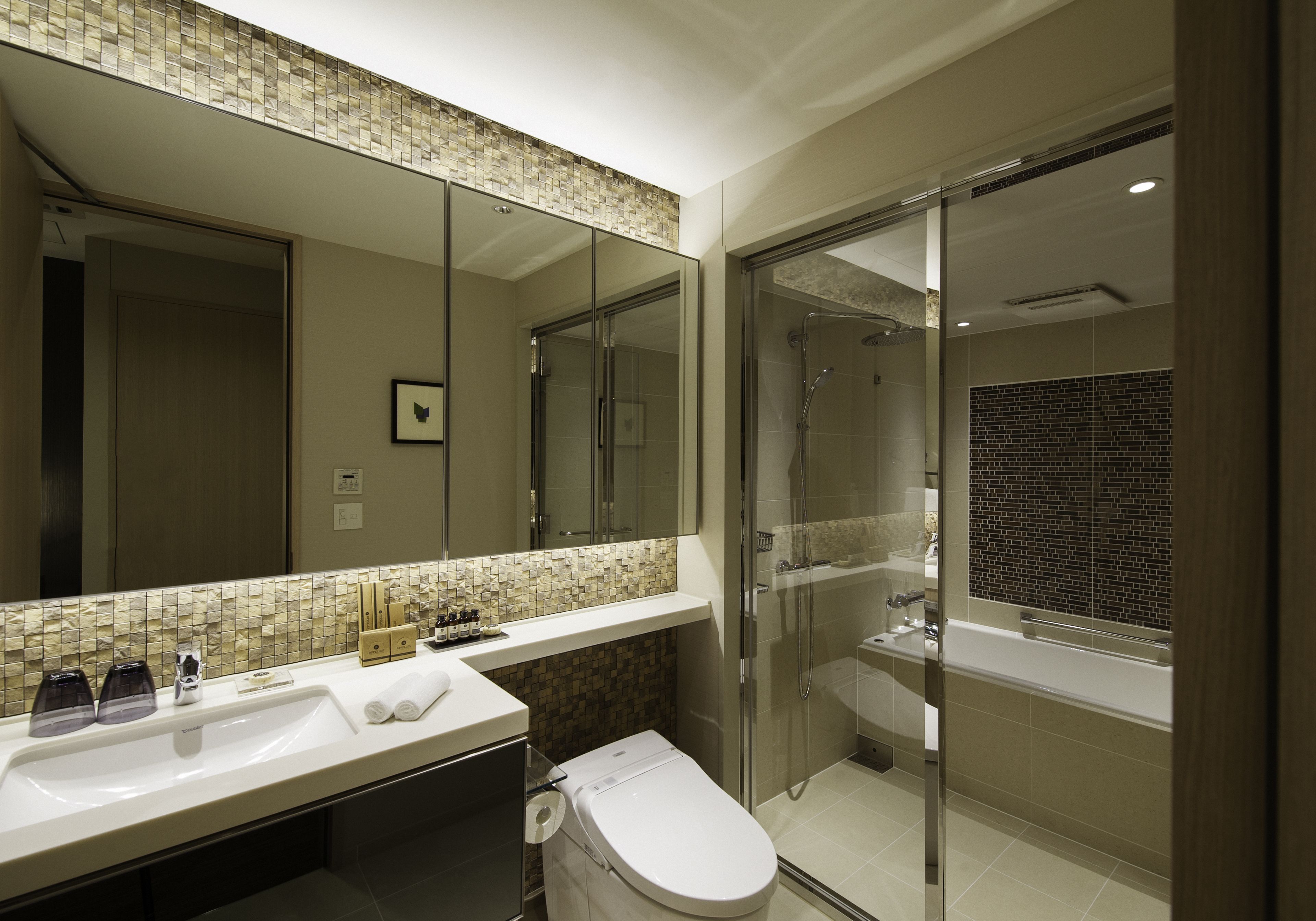 A modern bathroom with a glass-enclosed shower, a large mirror, and a tiled backsplash.