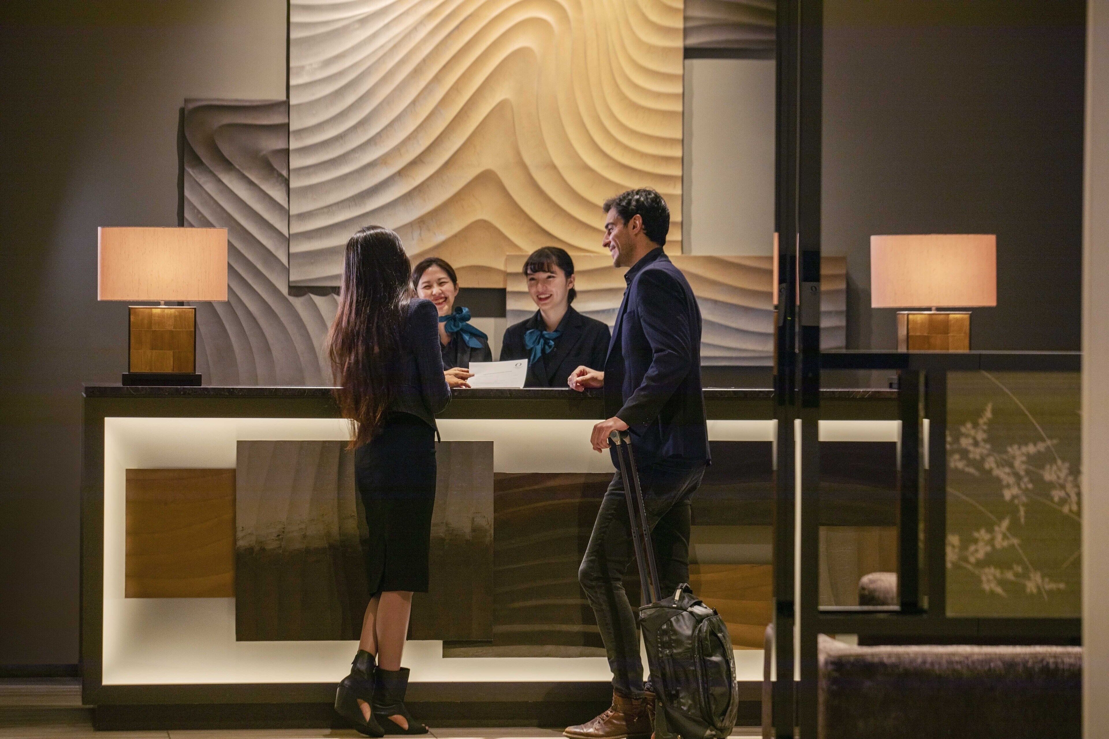 A reception desk with a modern design, a large mirror, and two lamps.