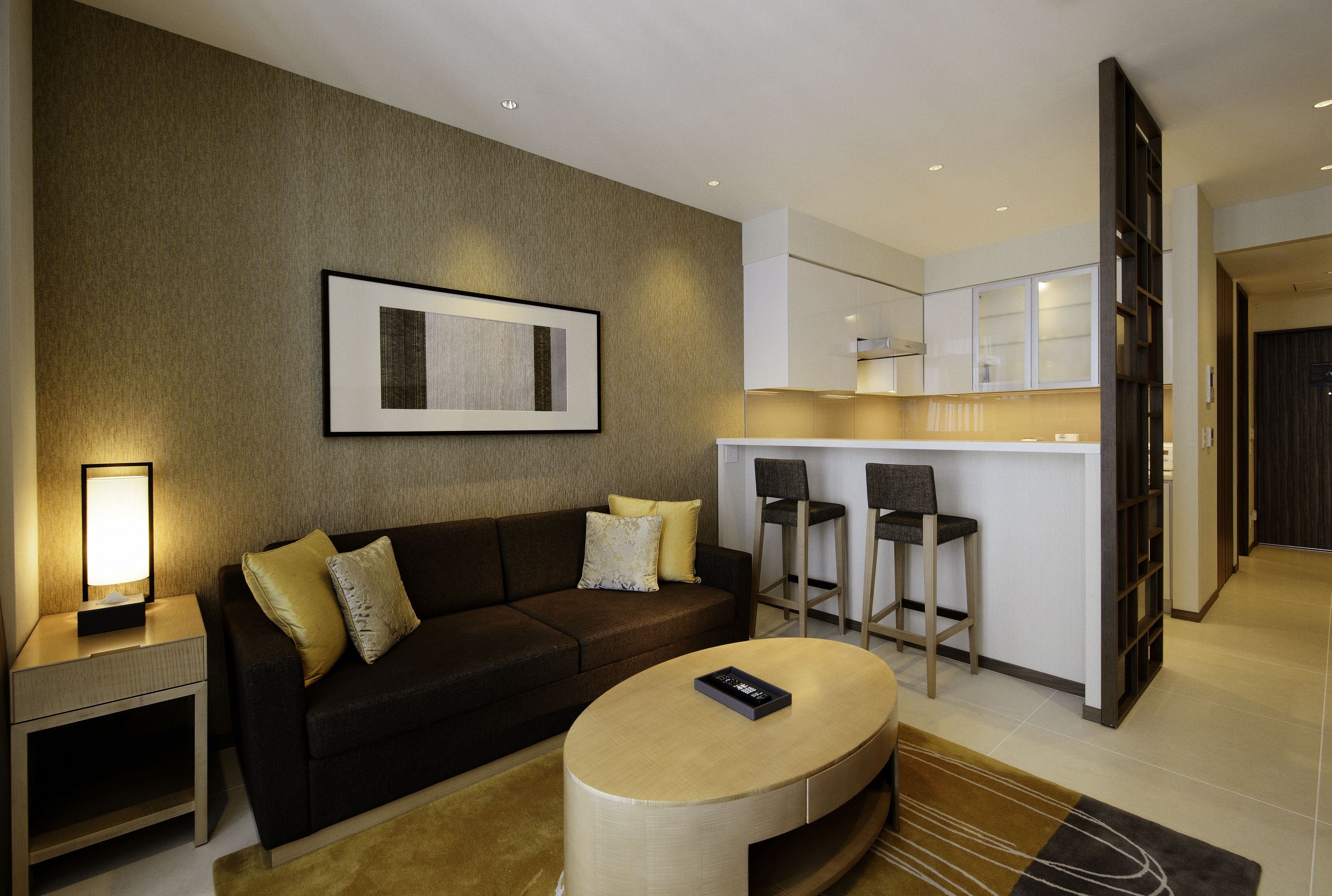 A modern living room with a sofa, a coffee table, and a kitchen area with bar stools.
