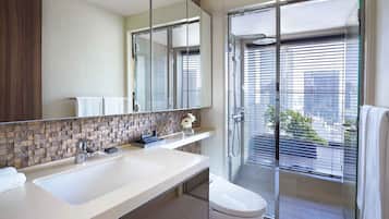A modern bathroom with a large mirror, two sinks, a toilet, and a glass-enclosed shower area.