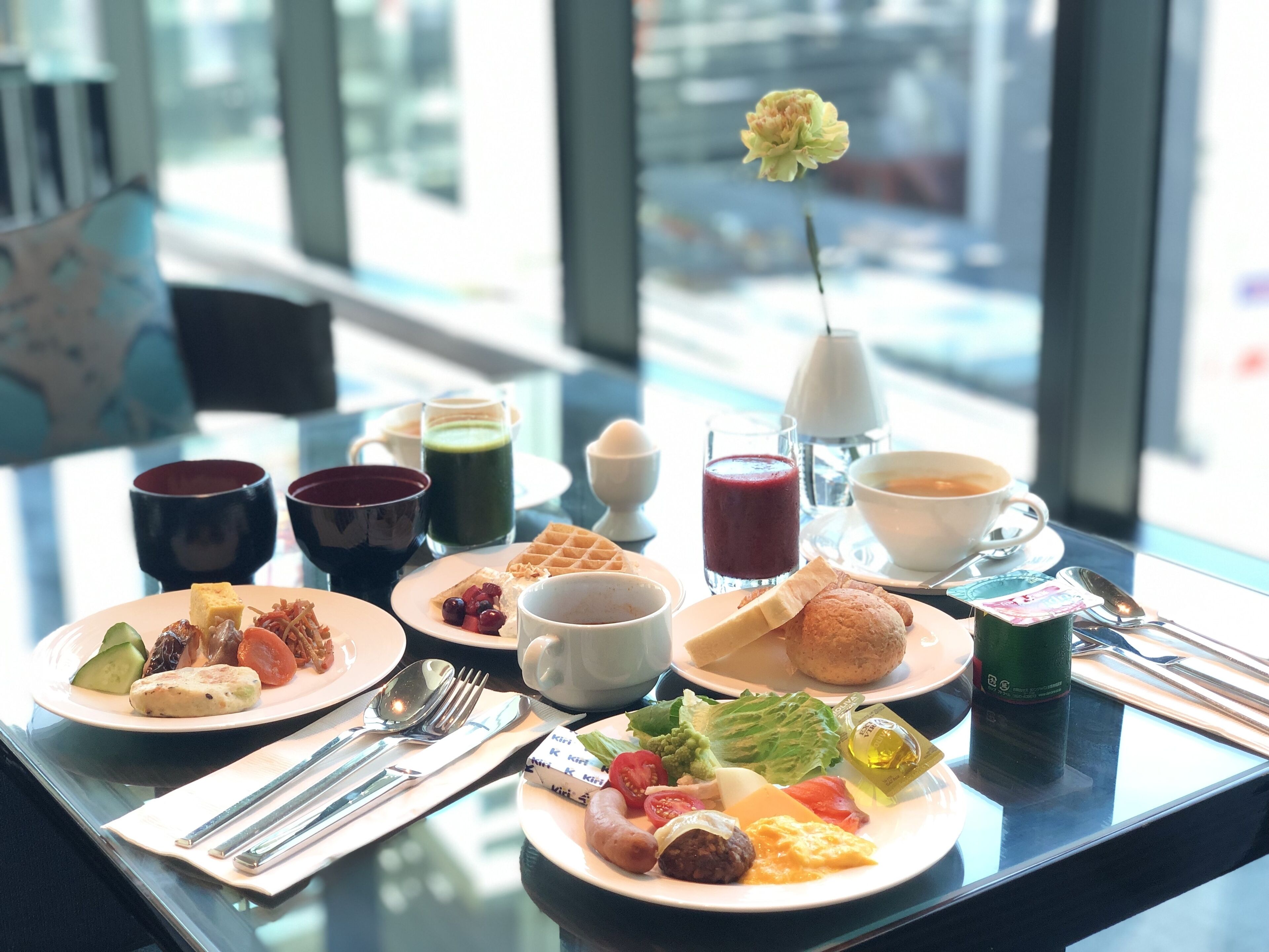 Une table de petit-déjeuner avec différents plats, boissons et ustensiles.