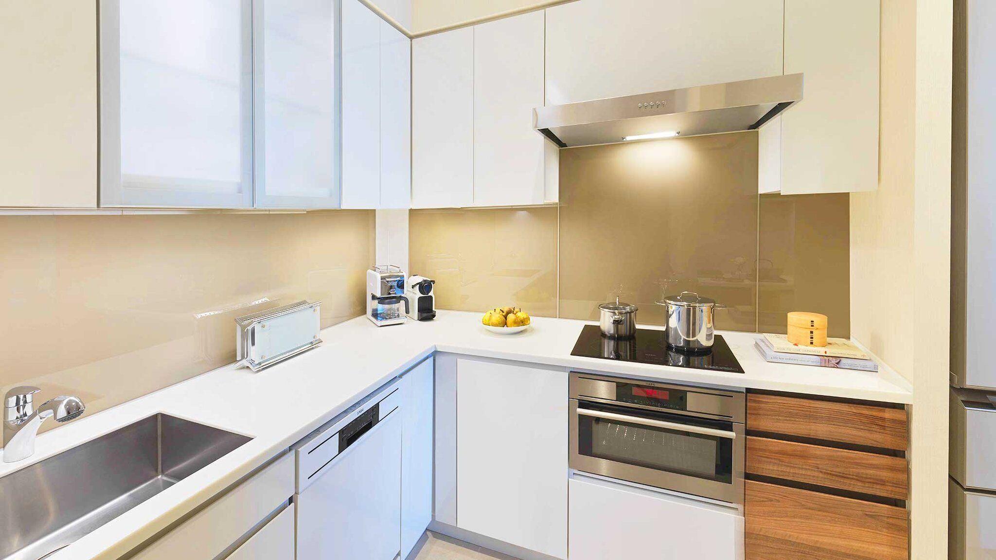 A modern kitchen with white cabinets, a stainless steel sink, a built-in oven, and a microwave.