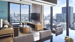 Una sala de estar moderna con vista a la ciudad, un televisor de pantalla plana y un comedor con mesa de vidrio.