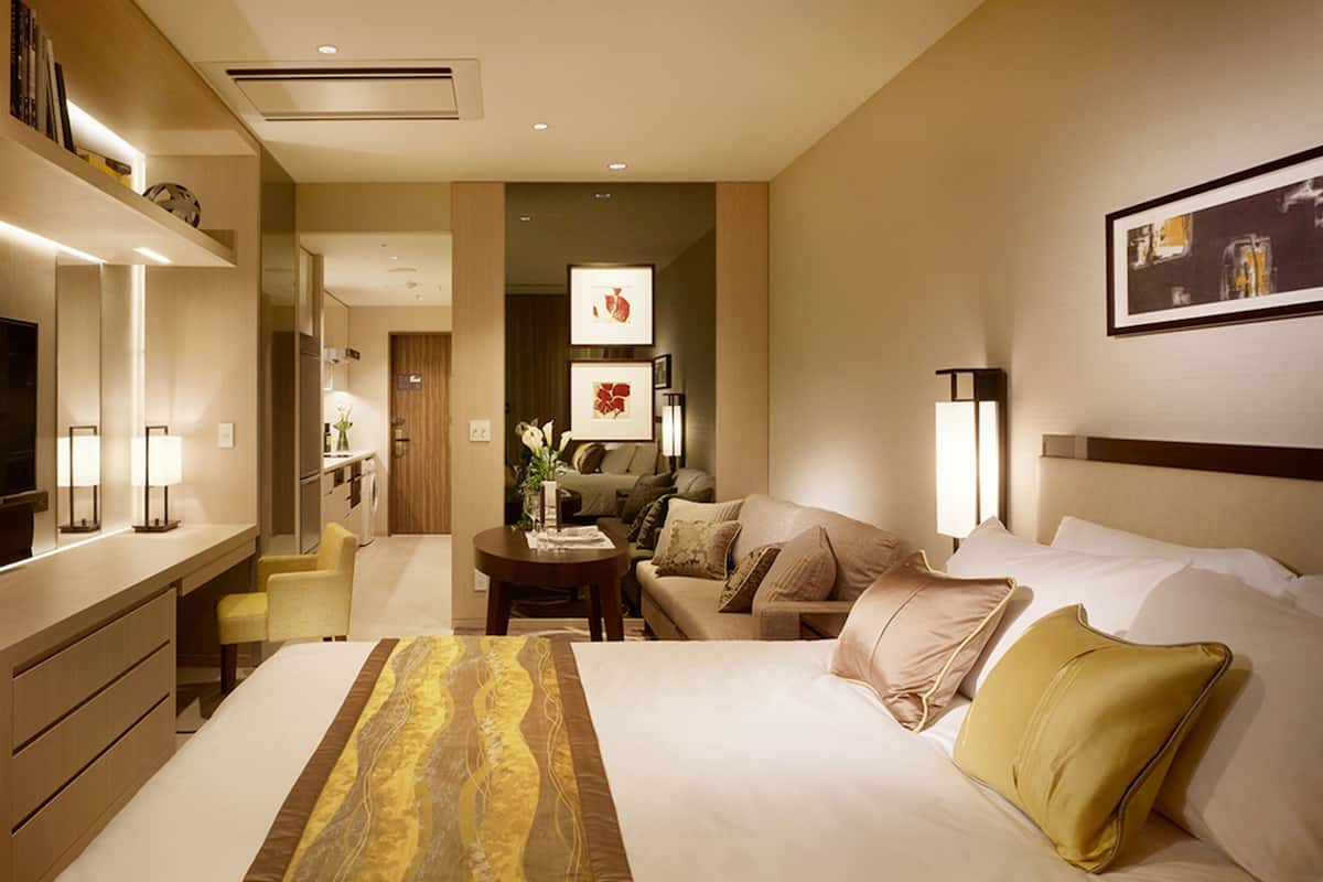 Una habitació d'hotel amb un llit, un escriptori, una cadira, un sofà i una taula de menjador.