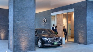 Un coche negro estacionado frente a un edificio con un letrero que dice "Oakwood Premier Tokyo".