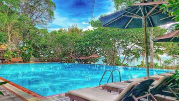 Una piscina al aire libre, sillones reclinables de piscina