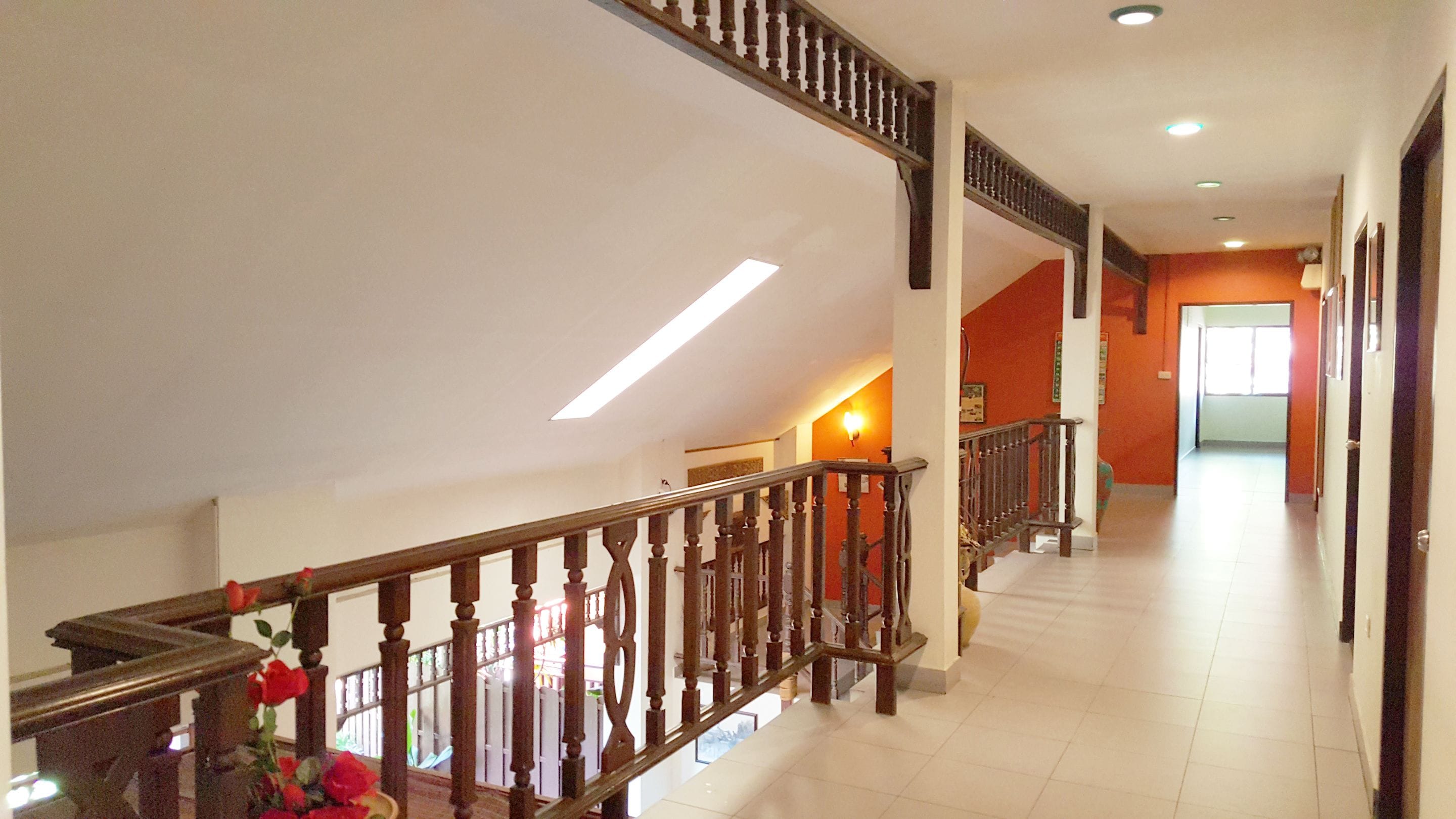 Un ampio corridoio con una scala in legno, una lampada a soffitto e una porta in fondo.