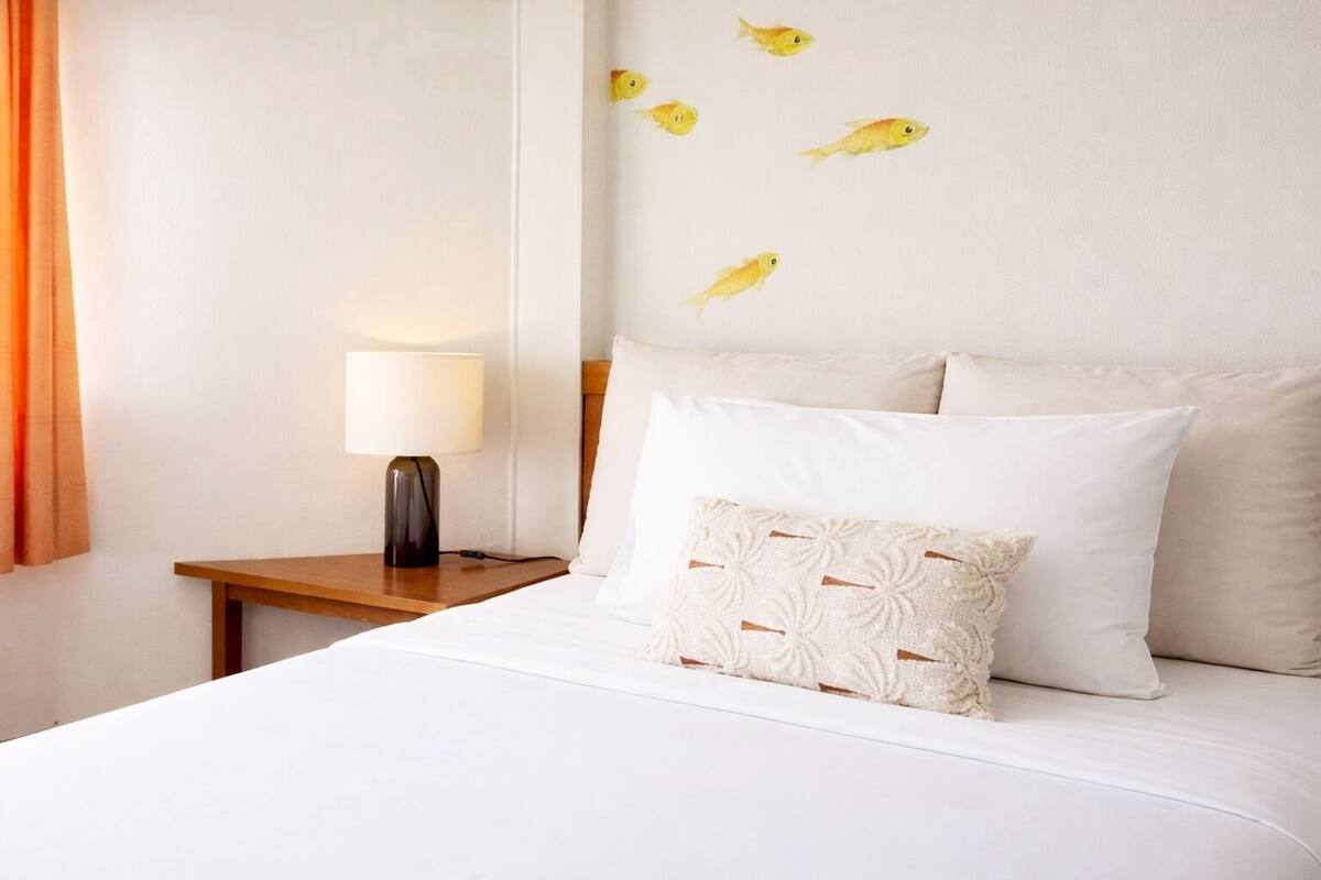 A hotel room with a bed, a nightstand with a lamp, and a wall with fish decals.