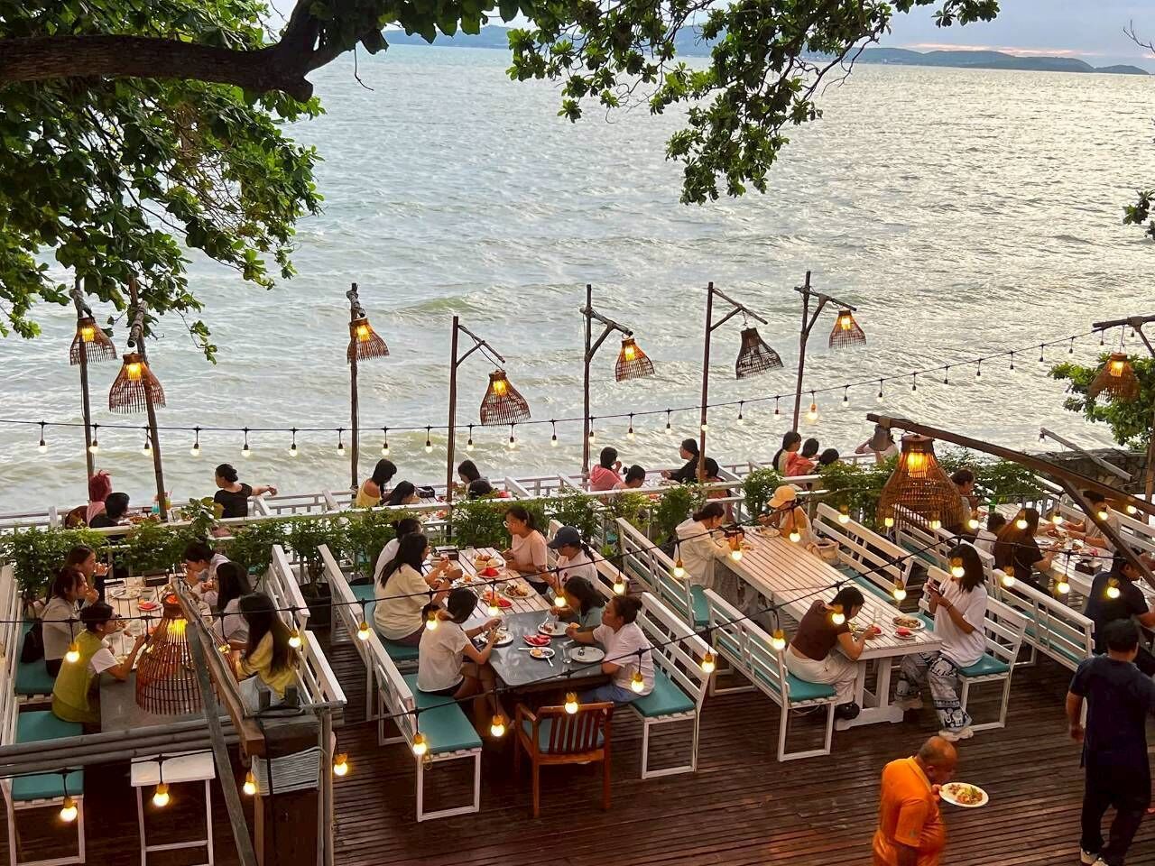 A dining area with tables and benches, overlooking a body of water.