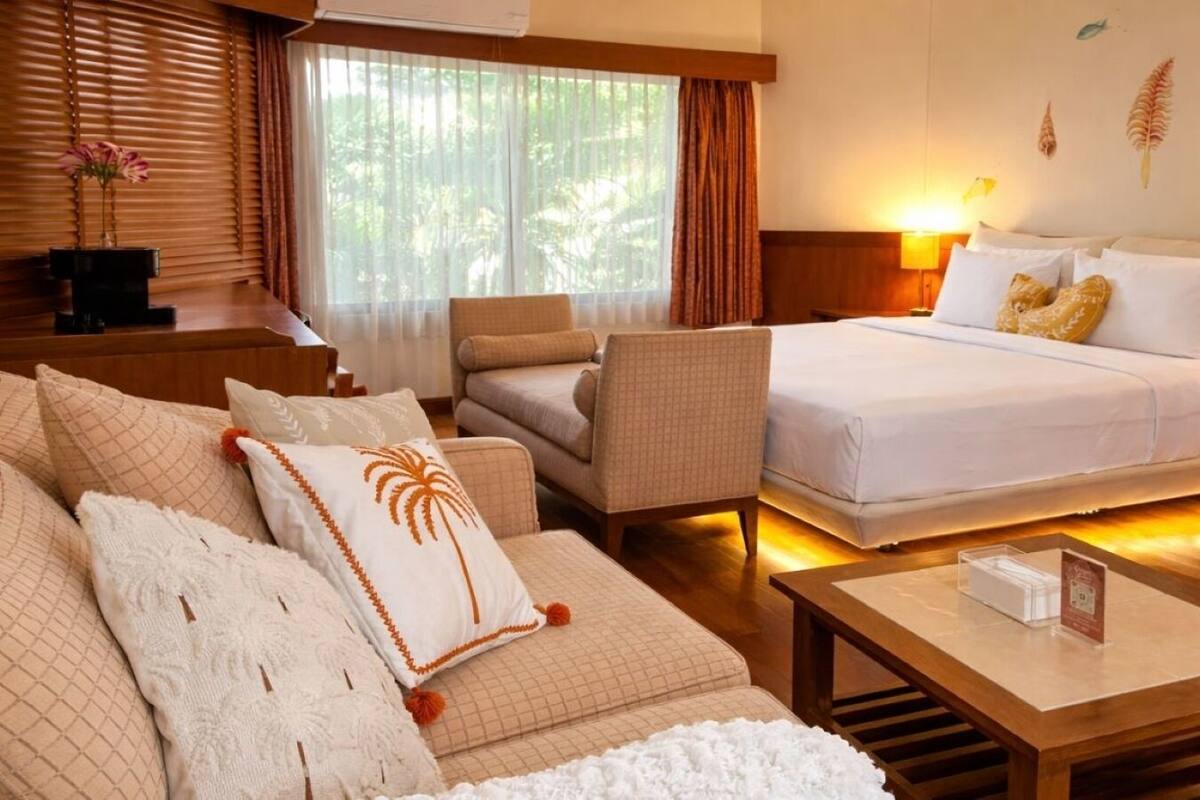 A hotel room with a bed, two armchairs, a sofa, a coffee table, and a nightstand.