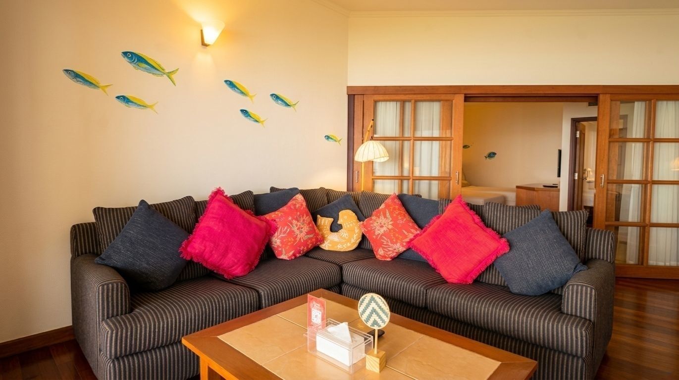 Ein Wohnzimmer mit gestreiften Sofas, bunten Kissen, einem Holztisch und Fischdekorationen an der Wand.