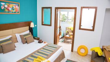 Une chambre d’hôtel avec un grand lit, une tête de lit en bois, une table de chevet avec une lampe, une œuvre d’art colorée au mur et une vue sur le balcon extérieur.