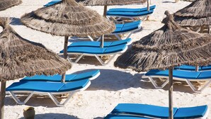 A beach with thatched umbrellas and blue lounge chairs arranged in rows. - AQI Skanes Resort (Monastir)