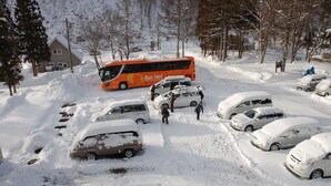 A snow-covered parking lot with several cars and a bus. - Hotel Mont Blanc Hakuba (Hakuba)