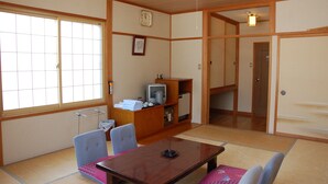 A traditional Japanese room with tatami flooring, a wooden table, a television, and a sliding door. - Hotel Mont Blanc Hakuba (Hakuba)