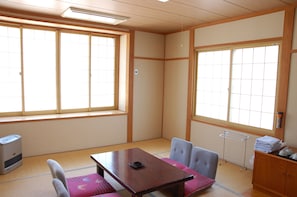 Um quarto japonês tradicional com tatames, uma mesa baixa e portas corrediças.