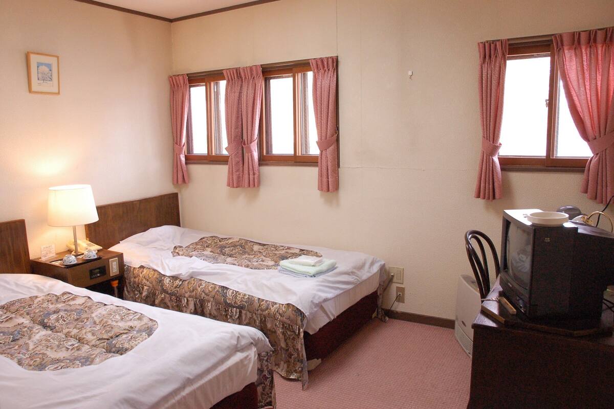 Habitació d'hotel amb dos llits, televisió i una làmpada.
