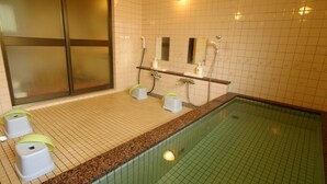 A bathroom with a tiled floor, a granite countertop, a shower area, and a toilet with a privacy partition. - Hotel Mont Blanc Hakuba (Hakuba)