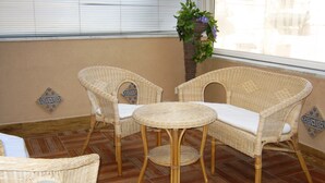 A room with wicker furniture, including two chairs and a small table, on a wooden floor. - Casa Aurelia (Palermo)