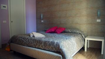 A bedroom with a bed, a bedside table, and a wall-mounted light fixture.