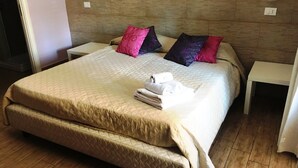 A hotel room with a large bed, two bedside tables, and a wooden floor. - Casa Aurelia (Palermo)