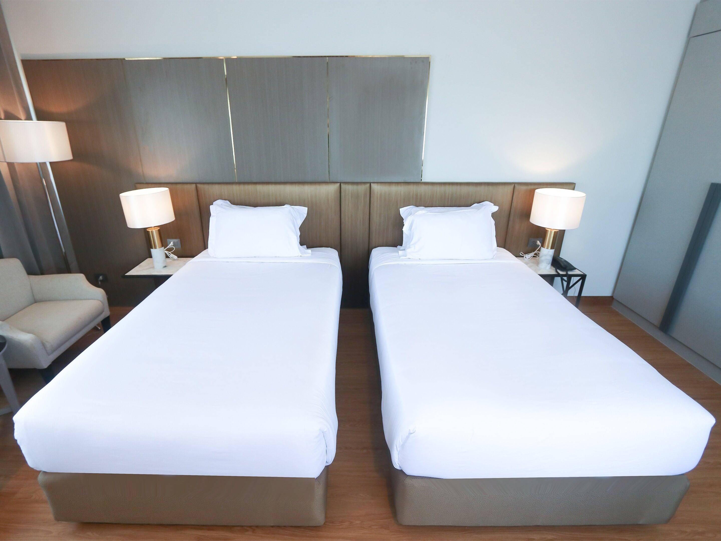 A hotel room with two single beds, a sofa, and two bedside lamps.