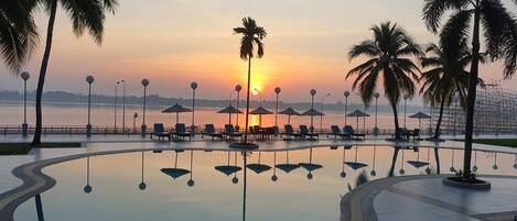 Alberca al aire libre, sombrillas en la alberca y camastros