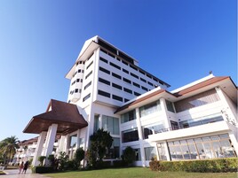 Un hotel de varios pisos con un diseño arquitectónico moderno, que destaca por una entrada prominente con zona cubierta y un césped bien cuidado.