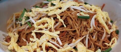 Un tazón de fideos cubierto con huevos revueltos y brotes de soja.