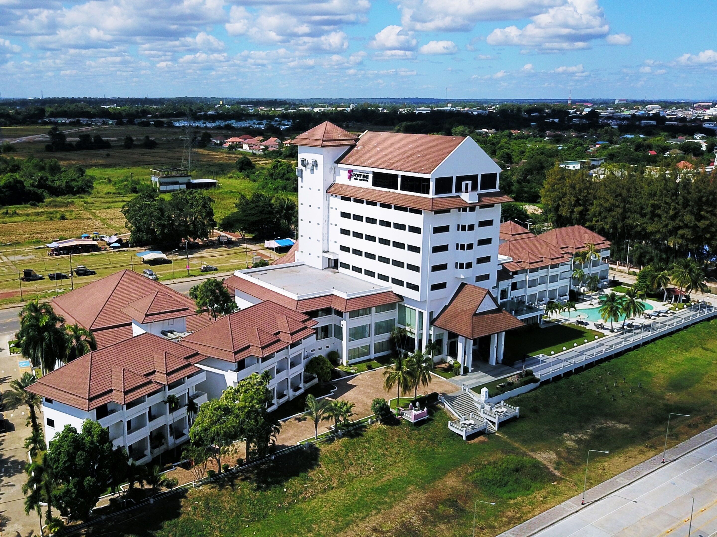 A multi-story hotel with a central tower, multiple wings, and a swimming pool.