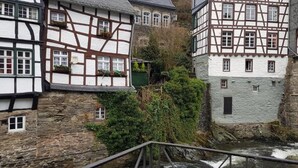 A narrow stone bridge connecting two buildings with traditional half-timbered facades. - Hotel Horchem (Monschau)