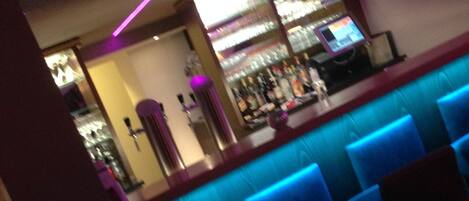 A bar area with blue illuminated seating and a counter displaying various bottles.