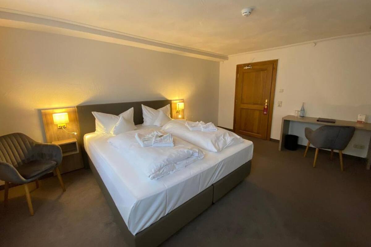 Ein Hotelzimmer mit einem großen Bett, einem Schreibtisch, einem Sessel und zwei Nachttischlampen.
