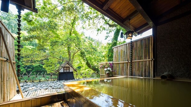 A traditional Japanese onsen with a wooden deck, a small house, and bamboo walls. - Hazuki (Shinshiro)