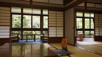 A traditional Japanese room with tatami flooring, sliding doors, and a view of greenery outside.