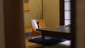 A traditional Japanese room with tatami flooring, a low wooden table, and a chair with a blue cushion.